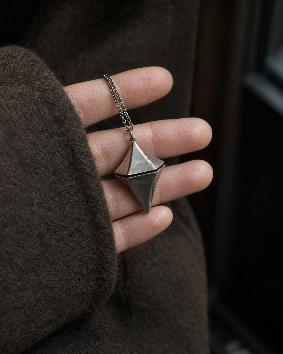 Concept scale image of the small geometric Glimmer pendant resting on fingertips